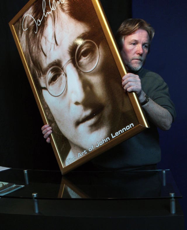 Art dealer Jonathan Poole installs a promotional poster for a John Lennon exhibition at The Dome in Edinburgh (David Cheskin/PA)