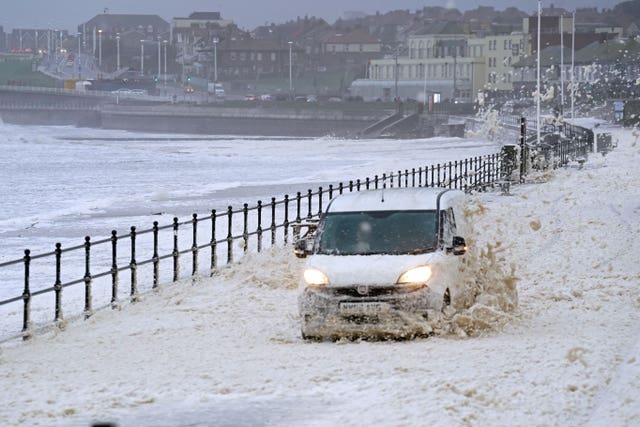 A van drives through sea foam in Seaburn, Sunderland