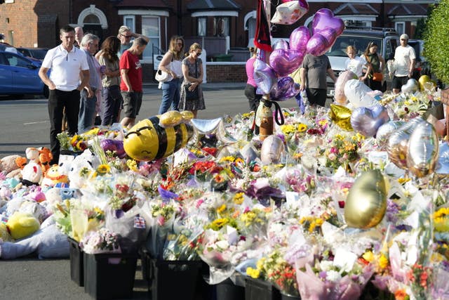 People look at floral tributes on Maple Street, Southport. 