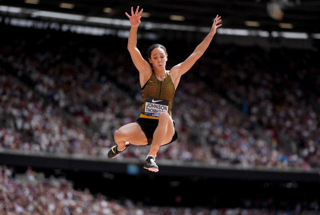 Katarina Johnson-Thompson in the air, arms outstretched, during a long jump effort. 