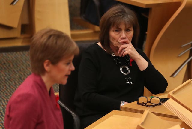Jean Freeman seated in Holyrood, watching on as Nicola Sturgeon speaks