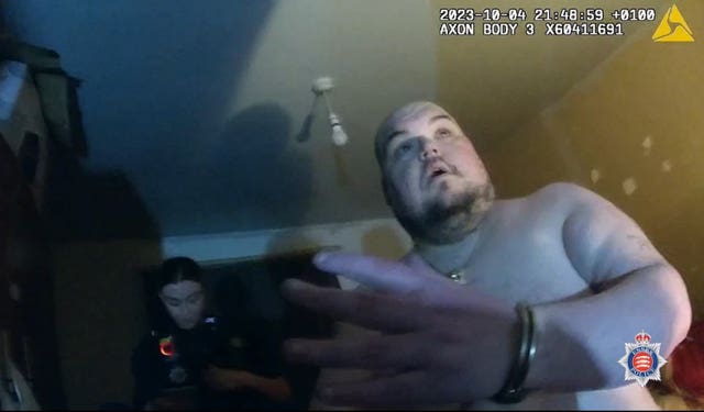 Gavin Plumb in handcuffs without his shirt on looking shocked at the arrest