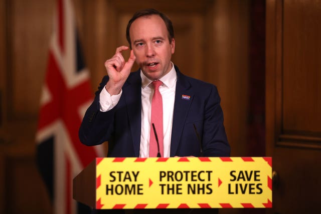 Matt Hancock standing behind a lectern with Covid messaging, during the pandemic