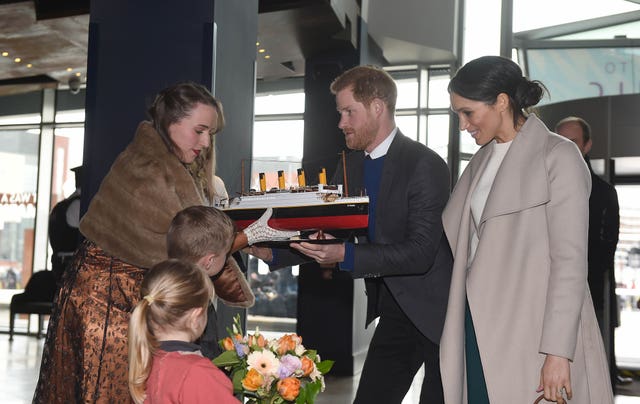 Prince Harry and Meghan Markle are presented with a model of the Titanic by Lleyton Jackson, six, and Rosie Jackson four, at Titanic Belfast maritime museum