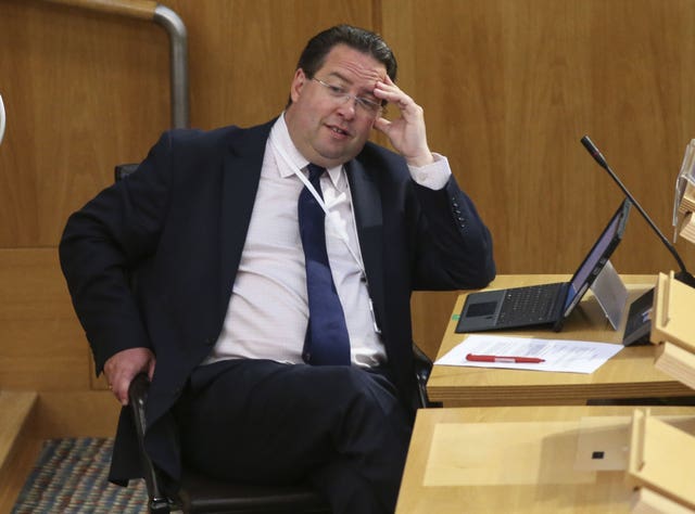 Craig Hoy resting his head on one hand in Parliament