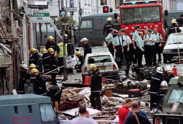 Police officers and firefighters inspect the damage caused by a bomb explosion in Market Street, Omagh 
