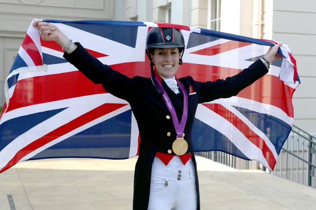 Charlotte Dujardin raising a Union Flag with her gold medal around her neck at London 2012.