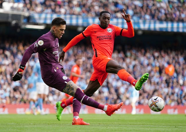 Manchester City goalkeeper Ederson clears the ball under pressure from Brighton's Danny Welbeck