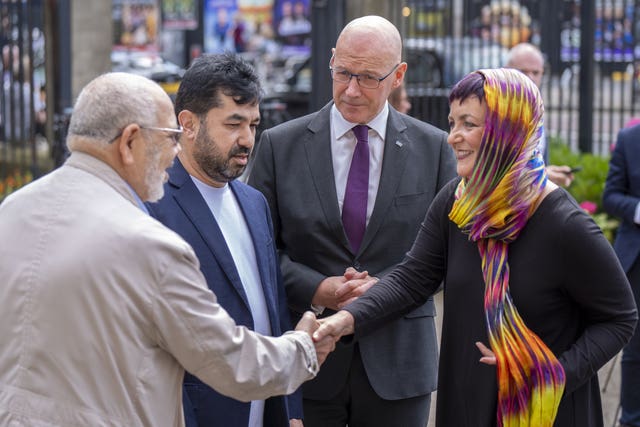 A woman shakes a man's hand as two other men watch