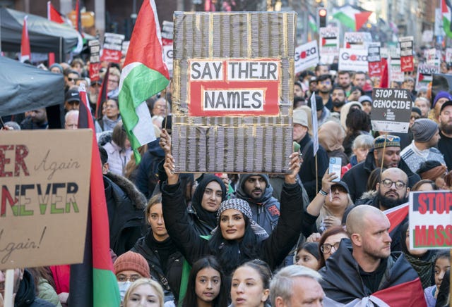 Woman holding a sign saying 'say their names' at a pro-Palestinian rally
