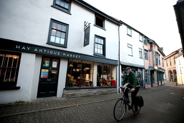 A man cycles past closed shops in Hay-on-Wye with Wales under a two-week “firebreak” lockdown (Nick Potts/PA)