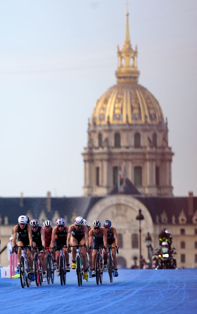 Women on bikes with a gold-topped building in the background