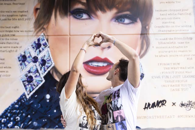 Fans pose in front a new mural that has been created to celebrate Swift's arrival in London 