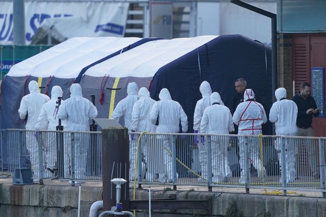 Police forensic officers head to forensic tents erected at the RNLI station at the Port of Dover following the search and rescue operation 