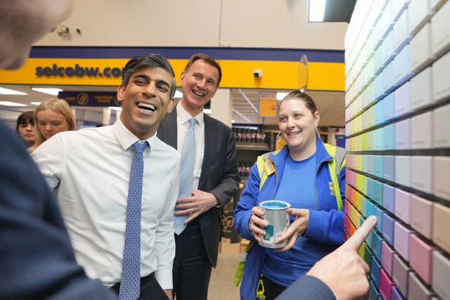 Prime Minister Rishi Sunak, Chancellor of the Exchequer Jeremy Hunt and staff member Charlene Kemal (right) watch as CEO of Selco, Howard Luft (left) points to a colour chart during a visit to a builders merchant in London. 