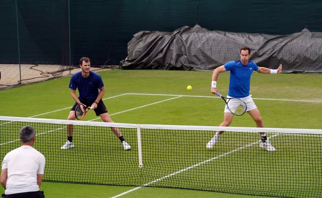 Andy Murray hits a backhand shot as brother Jamie watches on as the pair practise doubles