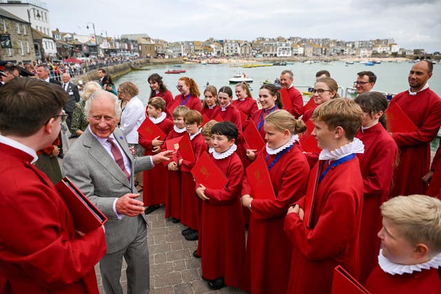 The King meets choristers from Truro Cathedral outside the RNLI station during a visit to St Ives Harbour (Finnbarr Webster/PA)