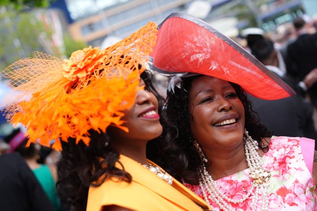 Two racegoers wear contrasting red and orange hats