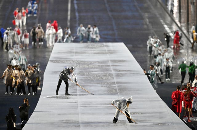 A member of staff sweeps rain off a walkway at the Trocadero during the opening ceremony of the Paris 2024 Olympic Games