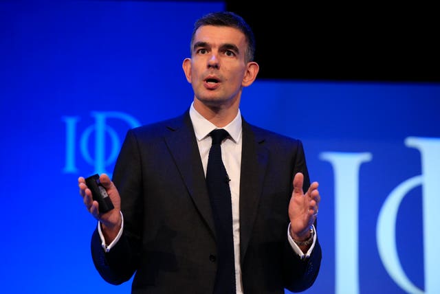 Matt Brittin in a black suit speaking on stage, with a blue background