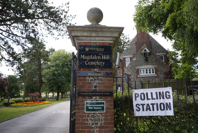 A polling station sign outside a cemetery