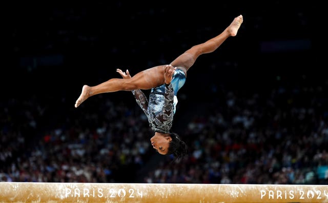 Simone Biles upside down as she somersaults on the balance beam