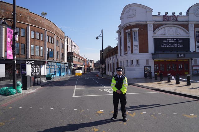 A police officer stands in front of a police cordon