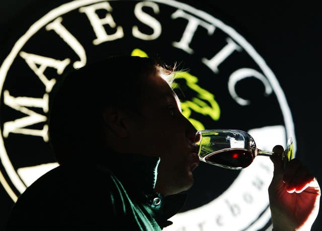 Someone drinking wine from a glass in front of a Majestic logo