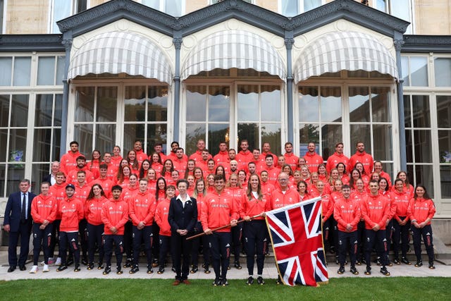 Members of Team GB in red kit with the Princess Royal, Helen Glover and Tom Daley holding a Union flag