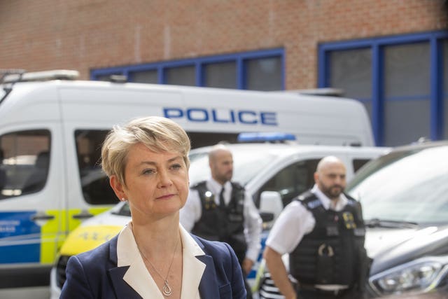 Home Secretary Yvette Cooper standing in front of police vans and officers