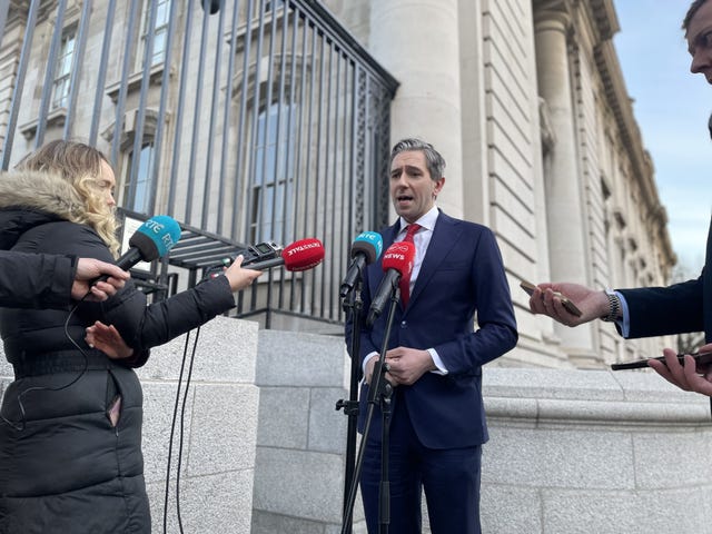 Simon Harris speaking outside into a bank of microphones