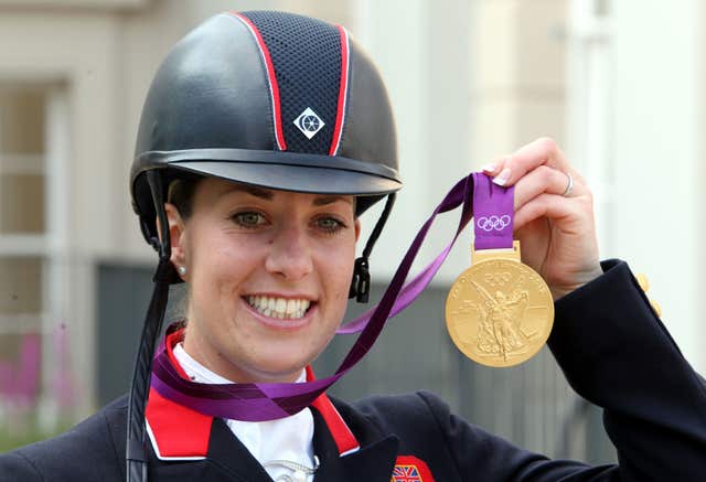 Charlotte Dujardin smiles and holds up the Olympic dressage gold she won at London 2012