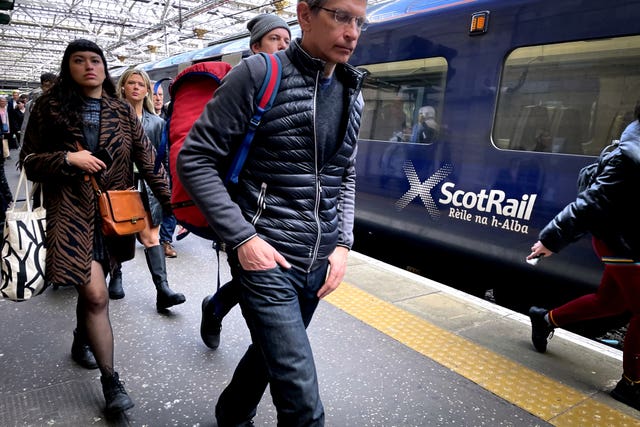 People walking on platform past ScotRail train