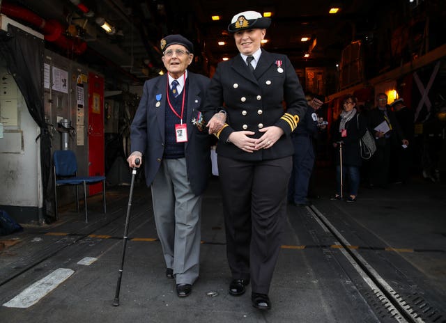 D-Day veteran Eric Strange, 95, who served with the Royal Navy, is escorted by Lieutenant Commander Charlotte Black to the flight deck on board HMS St Albans 