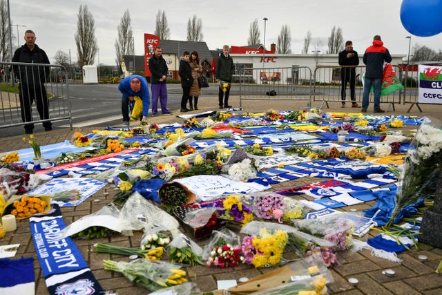 People lay flowers and tributes outside Cardiff City Football Club 