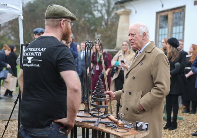 Charles talks with a blacksmith while admiring his work