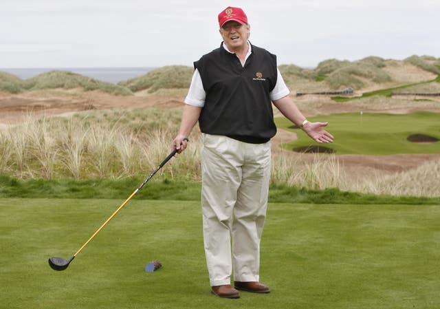 Donald Trump holding a golf club, standing on a golf course