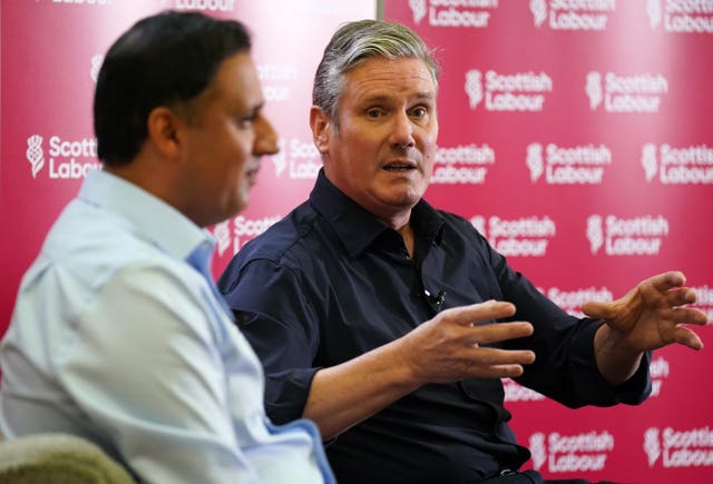 Keir Starmer and Anas Sarwar sit on stage with Scottish Labour background