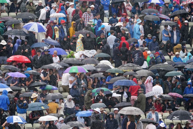 Fans sheltered under umbrellas during heavy rain during day three of the first Ashes test match at Edgbaston 