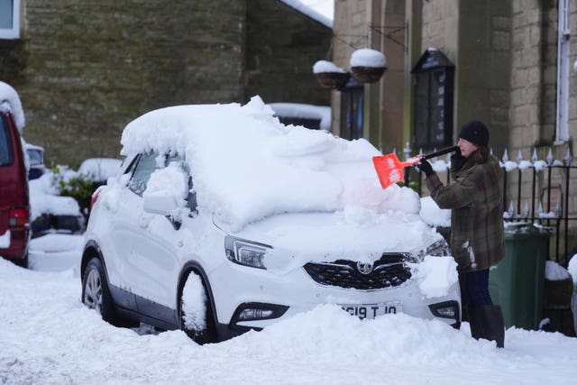 A person clears snow from a car in Allendale, Northumberland 