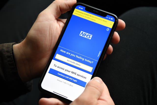 A person holding a mobile phone displaying the NHS app (Kirsty O'Connor/PA)