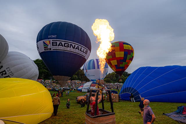 Hot air balloons flash the burners as they prepare to lift off