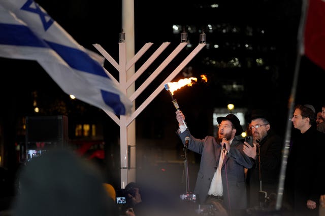 Rabbi Shimshon Gansbourg, nephew of Rabbi Eli Schlanger, who was murdered in the Sydney massacre, lighting the second candle in the menorah at a Campaign Against Antisemitism and Chabad UK event in Westminster, central London 