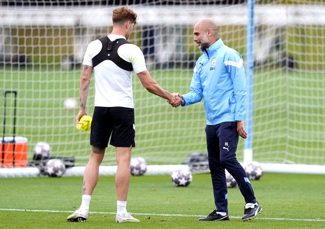 Manchester City manager Pep Guardiola shake hands with John Stones during a training session