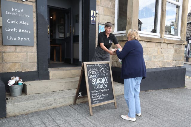A woman is handed an order of a Sunday lunch served from the Three Horseshoes public house in Leeds (Danny Lawson/PA)