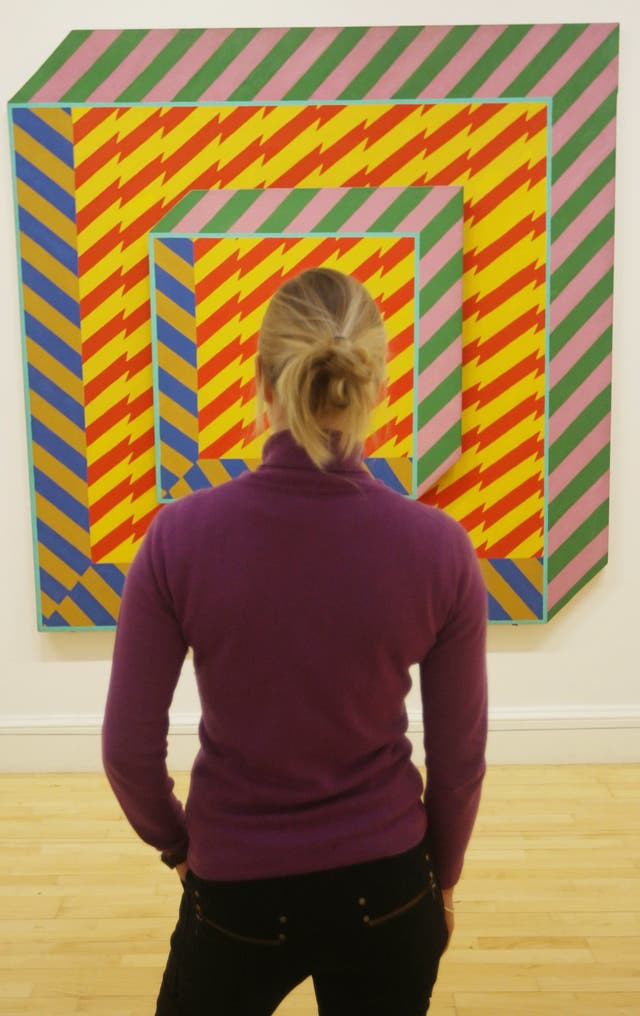 A woman with her back to the camera looks at an artwork in a gallery