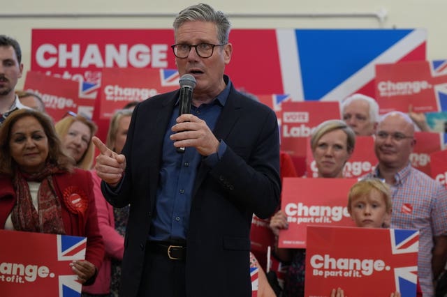 Sir Kier Starmer giving a speech in front of supporters holding red signs with the word 'change' written on them