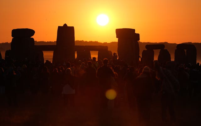 People watch the sun rise, as they take part in the Summer Solstice at Stonehenge