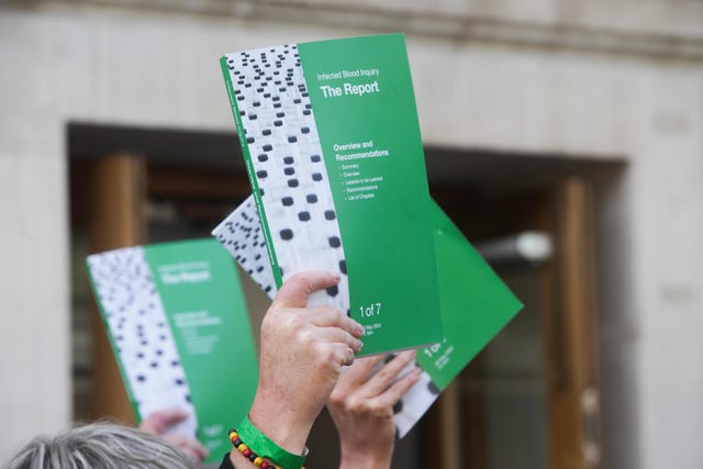 People holding up copies of the Infected Blood Inquiry report