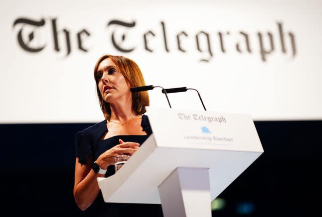 Camilla Tominey standing up in front of a sign which reads The Telegraph